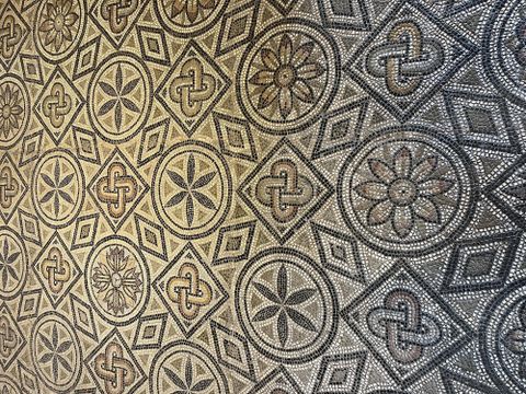 An elegant mosaic floor with various geometric patterns and floral motifs. The colors are kept in neutral tones, giving the design a classic look.