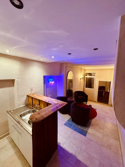 A modern interior view with a small kitchen and comfortable armchairs. The light creates a pleasant atmosphere.