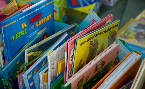 Eine Sammlung von bunten Kinderbüchern in verschiedenen Sprachen. Die Bücher sind auf einem Tisch gestapelt und vermitteln eine fröhliche Atmosphäre.