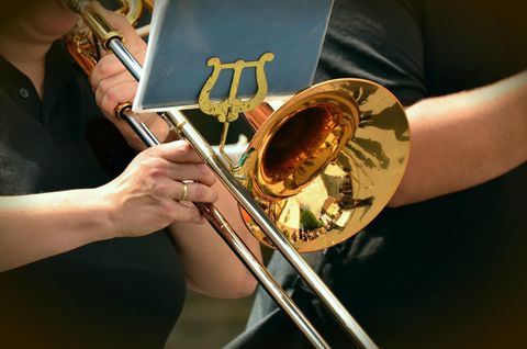 A trumpet is being held while it is played. The shiny surface reflects the light.