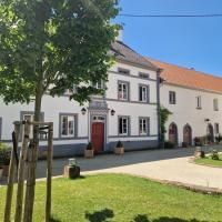 Une grande maison blanche avec un toit rouge.
Entourée de gazon vert et d'arbres par une journée ensoleillée.