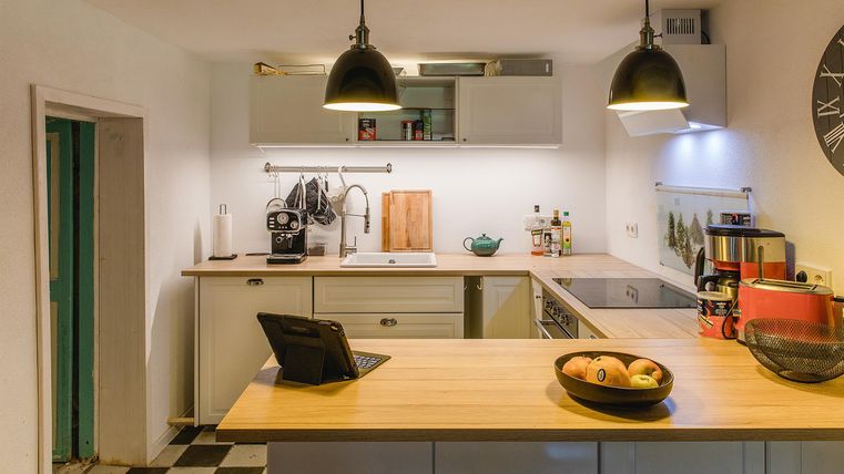 Eine moderne Küche mit einer Holzarbeitsplatte und schwarz-weißen Fliesen. Es gibt verschiedene Küchengeräte und ein stilvolles Design.