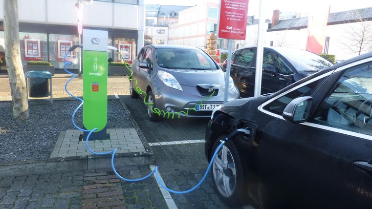 Eine Elektroauto-Ladestation mit zwei parkenden Autos. Eines der Autos wird gerade aufgeladen.